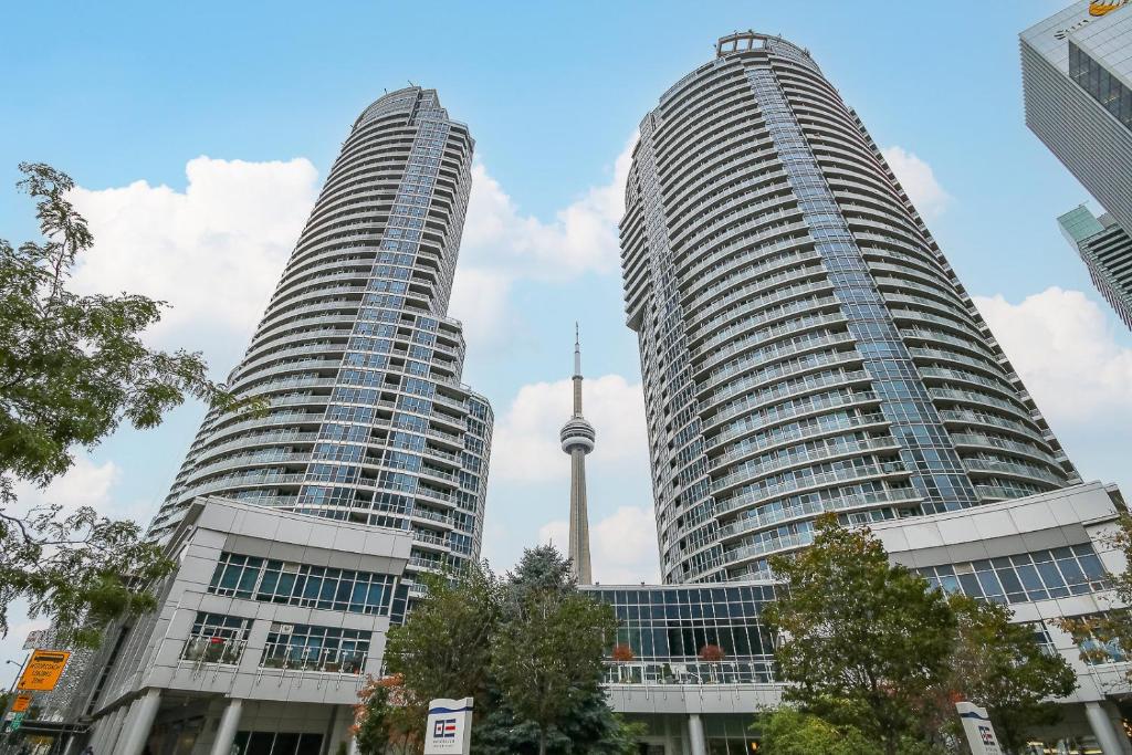 two tall buildings with a tv tower in the background at Panoramic Lakeview Resort Living 3BDR with Gym, Pool, Free parking in Toronto