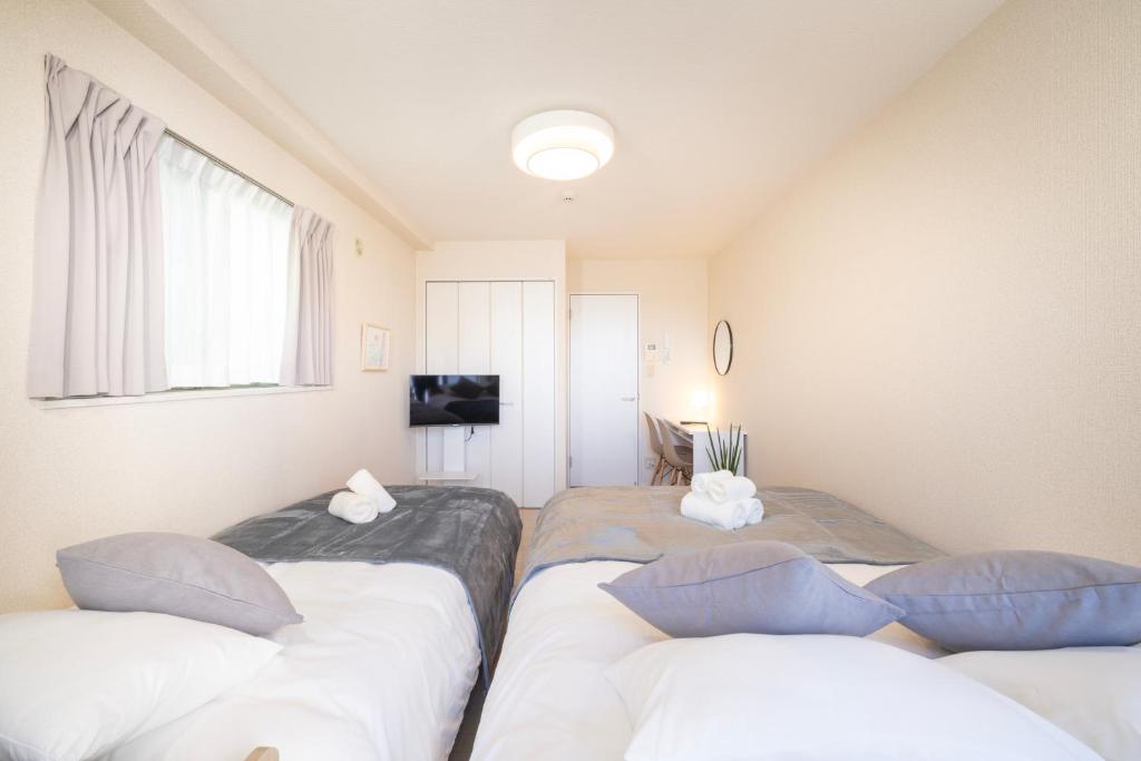 a room with two beds and a tv in it at BK Residence Kawasaki in Kawasaki