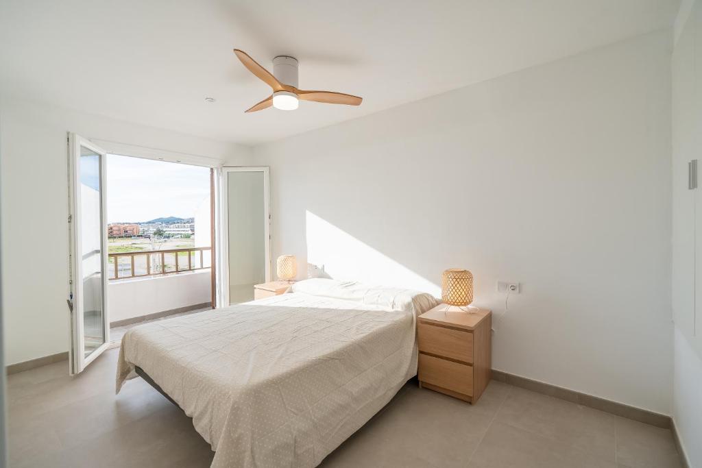 a white bedroom with a bed and a ceiling fan at Casa Ingravita - Oceanfront Tranquility in Cunit
