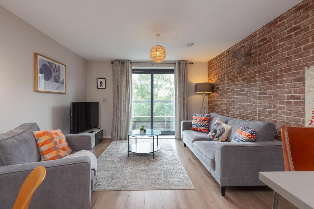 a living room with two couches and a brick wall at Lancaster City Apartment in Lancaster