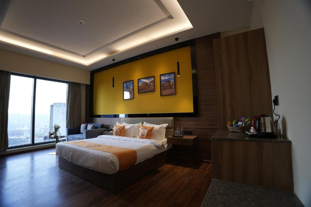 a hotel room with a bed and a yellow wall at The Murti Hotel and Banquet in Noida