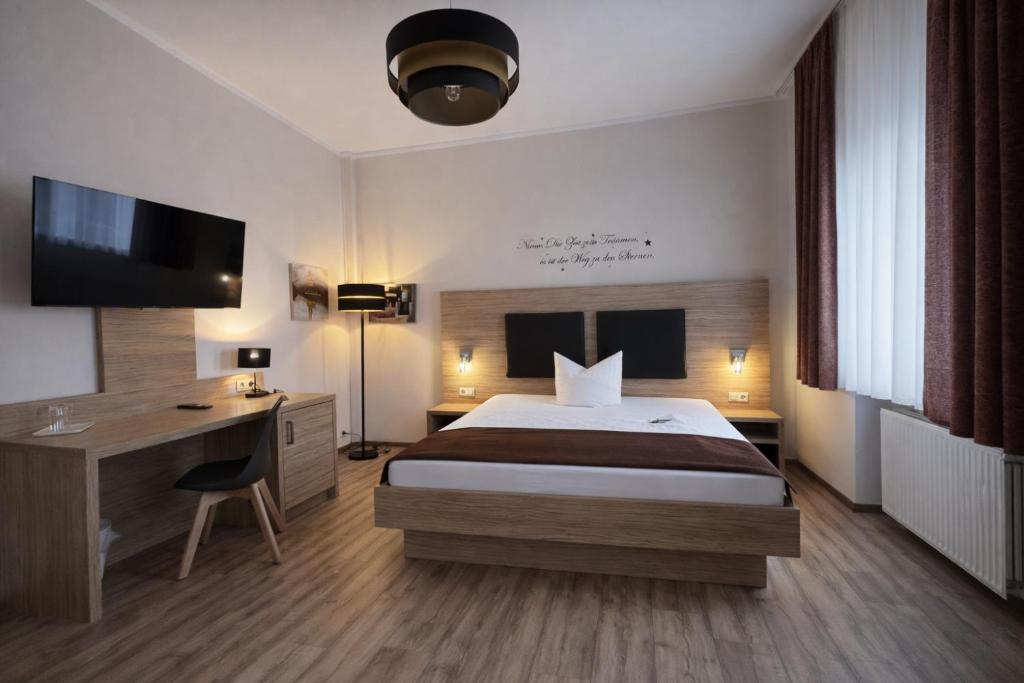 a bedroom with a bed and a desk and a television at Arena Hotel in Gelsenkirchen