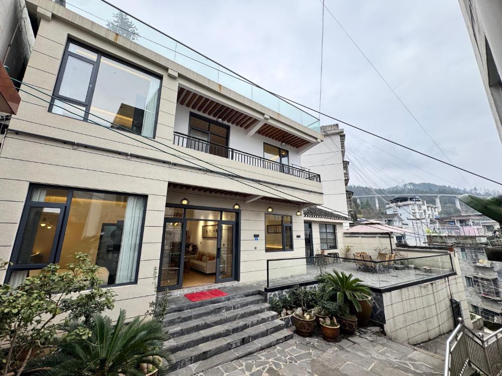 a white house with stairs and plants at 枫江月 in Fenghuang County