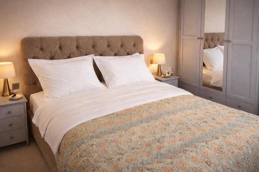 a bedroom with a large bed with two lamps and a mirror at Verdant Comfort Apartment in Moka