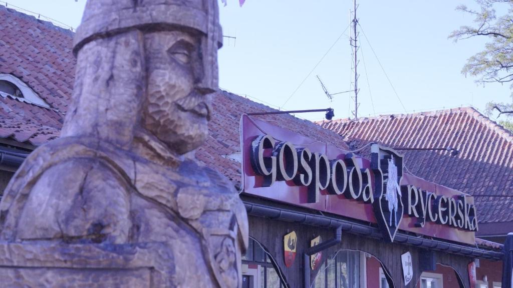 a sign on the side of a building with a statue at Gospoda Rycerska pod Grunwaldem in Grunwald