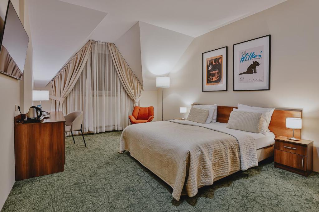 ein Hotelzimmer mit einem großen Bett und einem Stuhl in der Unterkunft Hotel Kantoria in Tarnów