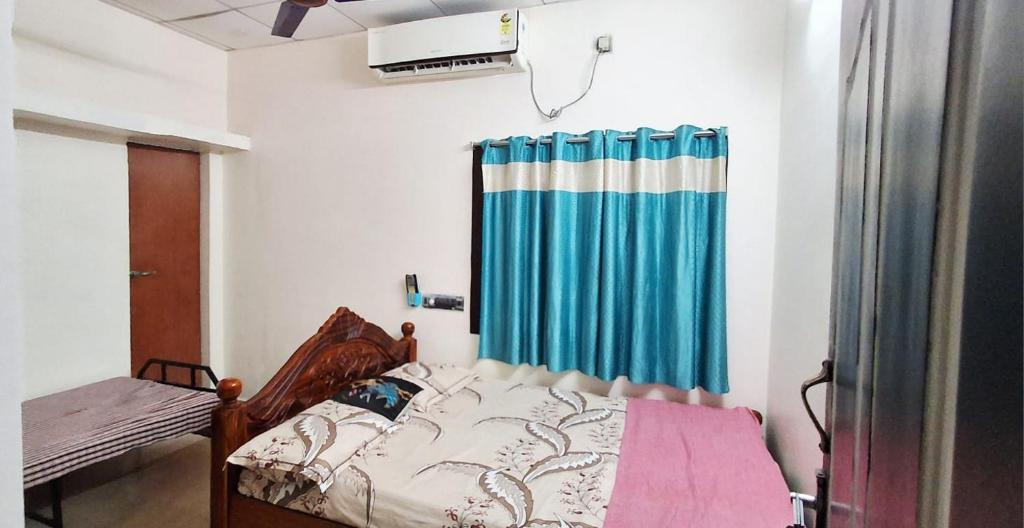 a bedroom with a bed and a blue curtain at Sripadakuteer in Pithāpuram