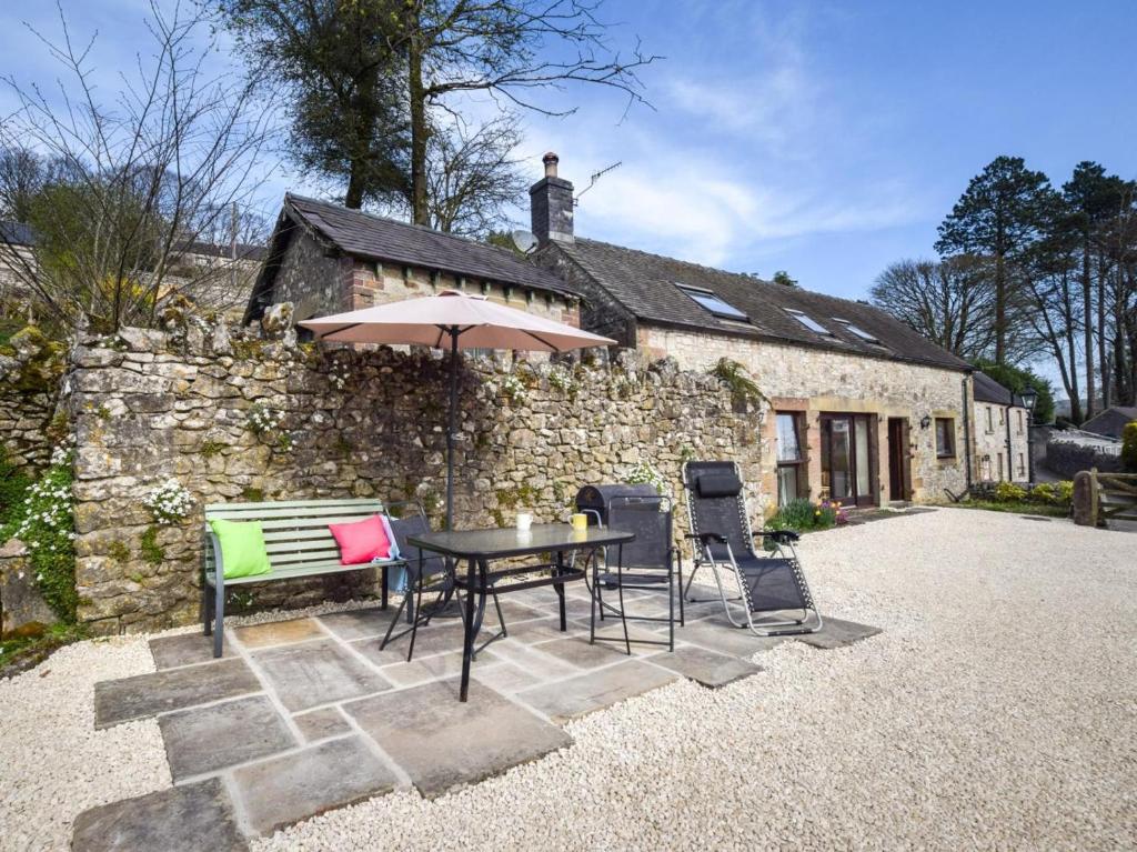 a table and chairs in front of a stone house at 2 Bed in Matlock oc-75893 in Smalley