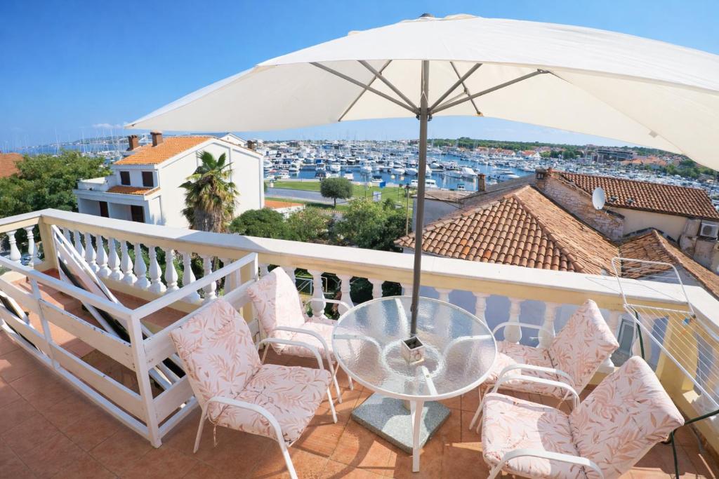 a glass table and chairs on a balcony with an umbrella at Orange city apartment's Repić in Biograd na Moru