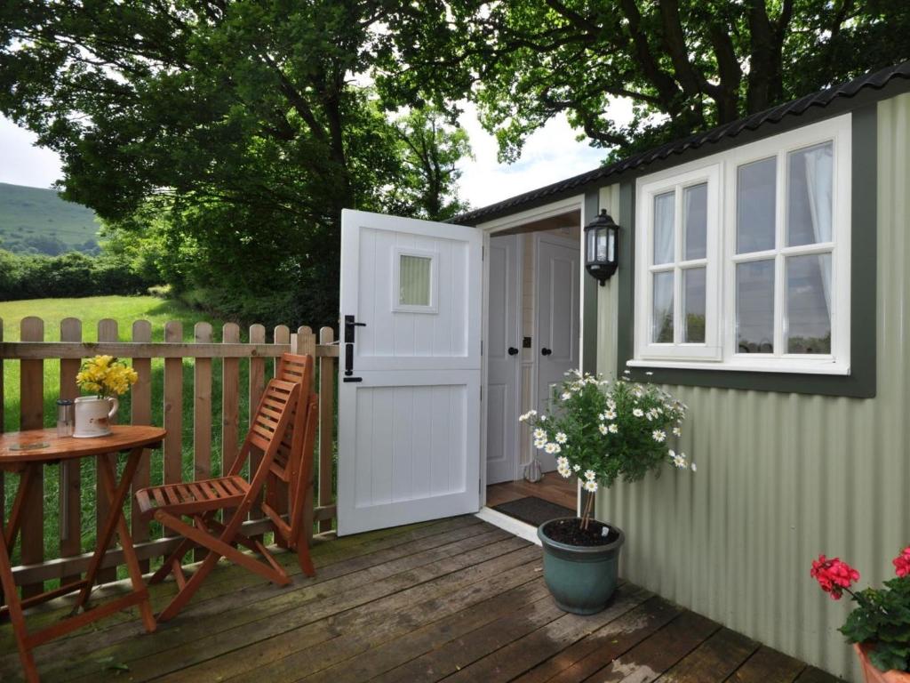 a green shed with a door and a table and a chair at 1 Bed in Hereford oc-44235 in Longtown
