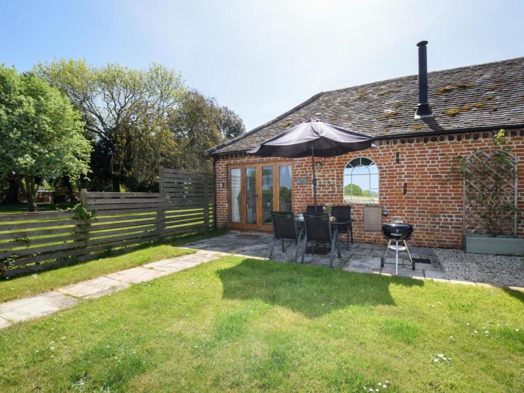 a patio with an umbrella and chairs and a grill at 2 Bed in Evesham oc-89305 in Church Lench