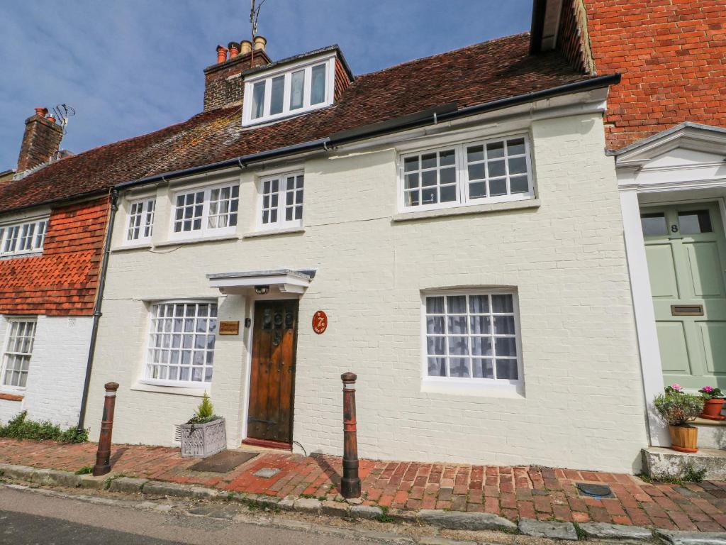 a white house with a brown door on a street at Quince Cottage in Lewes
