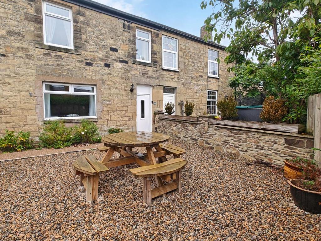 a picnic table and benches in front of a building at 3 Bed in Morpeth oc-96236 in Amble