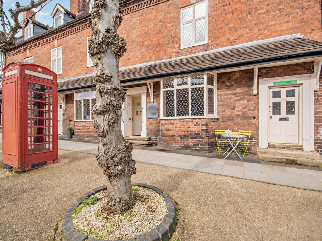 a red phone booth and a tree in front of a building at 1 Bed in Kidderminster oc-82957 in Cleobury Mortimer