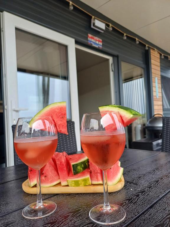 two glasses of red wine next to a plate of watermelon at Mobilhome Maja in Pirovac