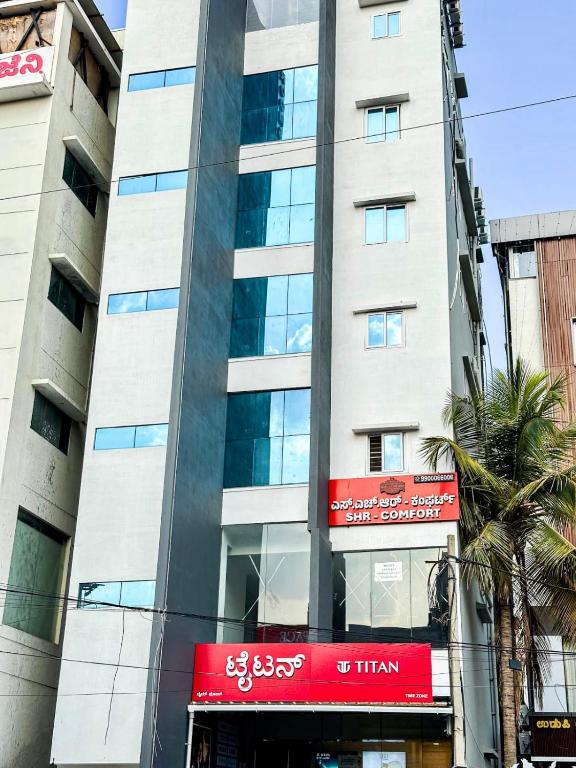 a tall building with a red sign in front of it at SHR Comfort Near Reva Circle Yelahanka in Bangalore