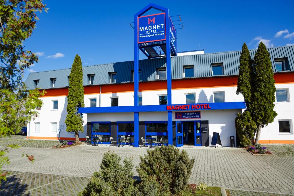 a large white building with a mavericks hotel at Magnet Hotel in Schkeuditz