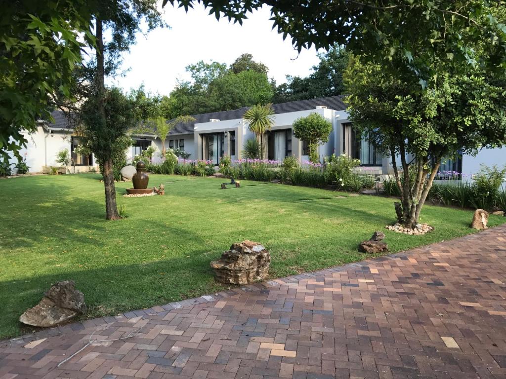 a house with a yard with trees and rocks at 6 on Morris Guest Lodge in Johannesburg