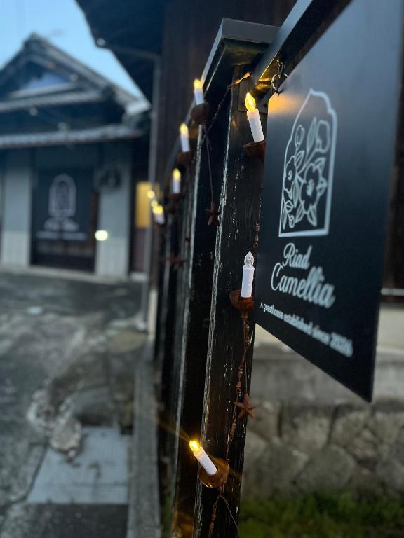 a sign on a fence with lights on it at Riad Camellia in Mitoyo