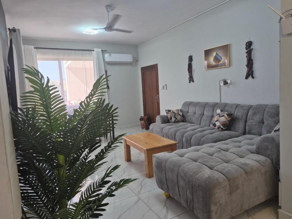 a living room with a couch and a palm tree at Furahi Apartment in Mombasa