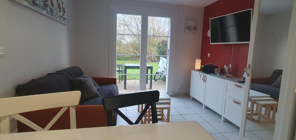 a living room with a couch and a television at Ma maison près du golf in Talmont