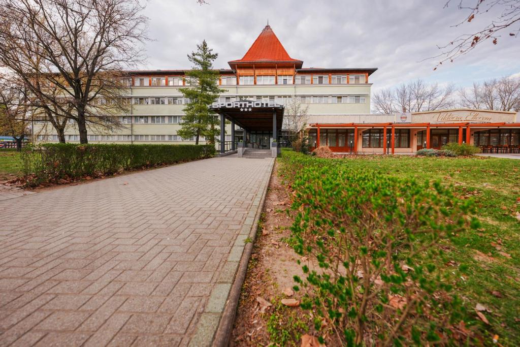 a building with a brick sidewalk in front of a building at Sport Hotel in Debrecen