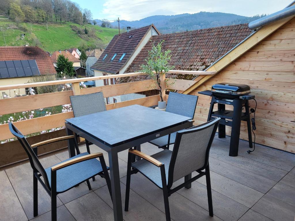 a table and chairs on a balcony with a grill at Printemps et Eté en Alsace in Stosswihr