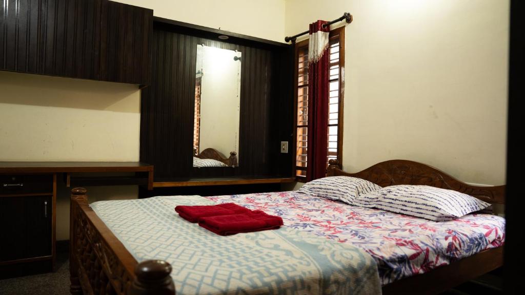 a bed with two red pillows and a mirror at DUDI's Stay in Mysore