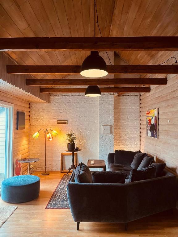 a living room with a black couch and a wooden ceiling at Penthouse in Farsund in Farsund
