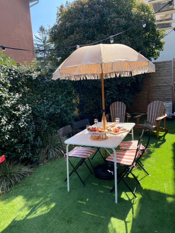 a table with an umbrella in a garden at Casita Valence - Petite maison de charme - Parking gratuit & Jardin Privé in Valence