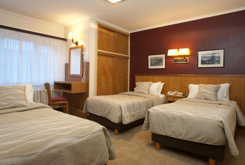 Habitación de hotel con 2 camas y escritorio en Hotel Milan en San Carlos de Bariloche