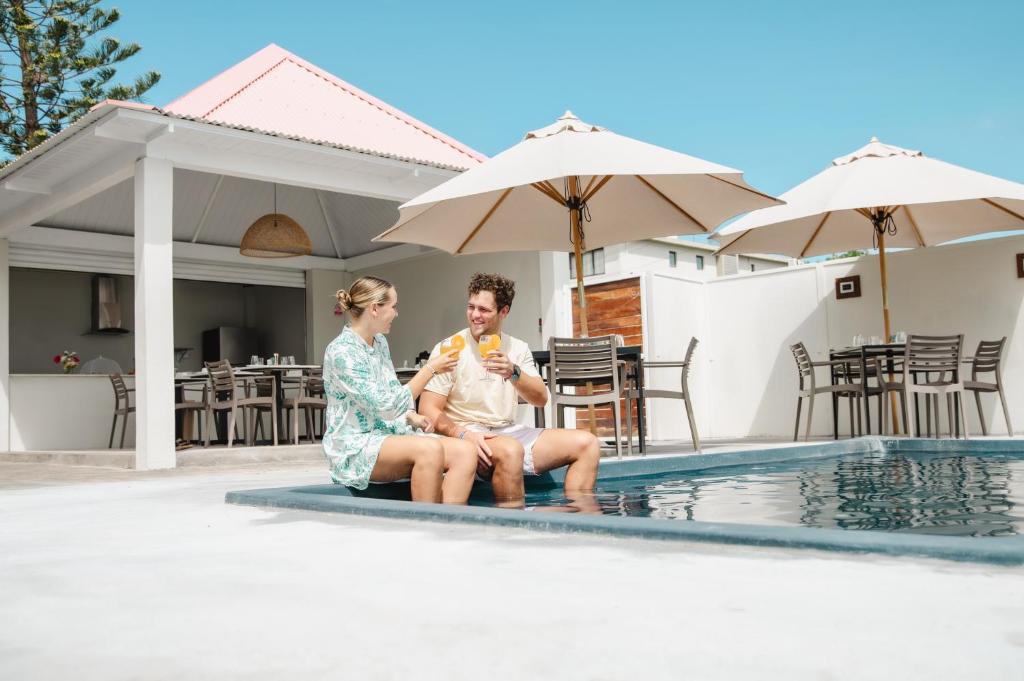 a man and woman sitting next to a swimming pool at Bois Bleu Bed And Breakfast in Tamarin