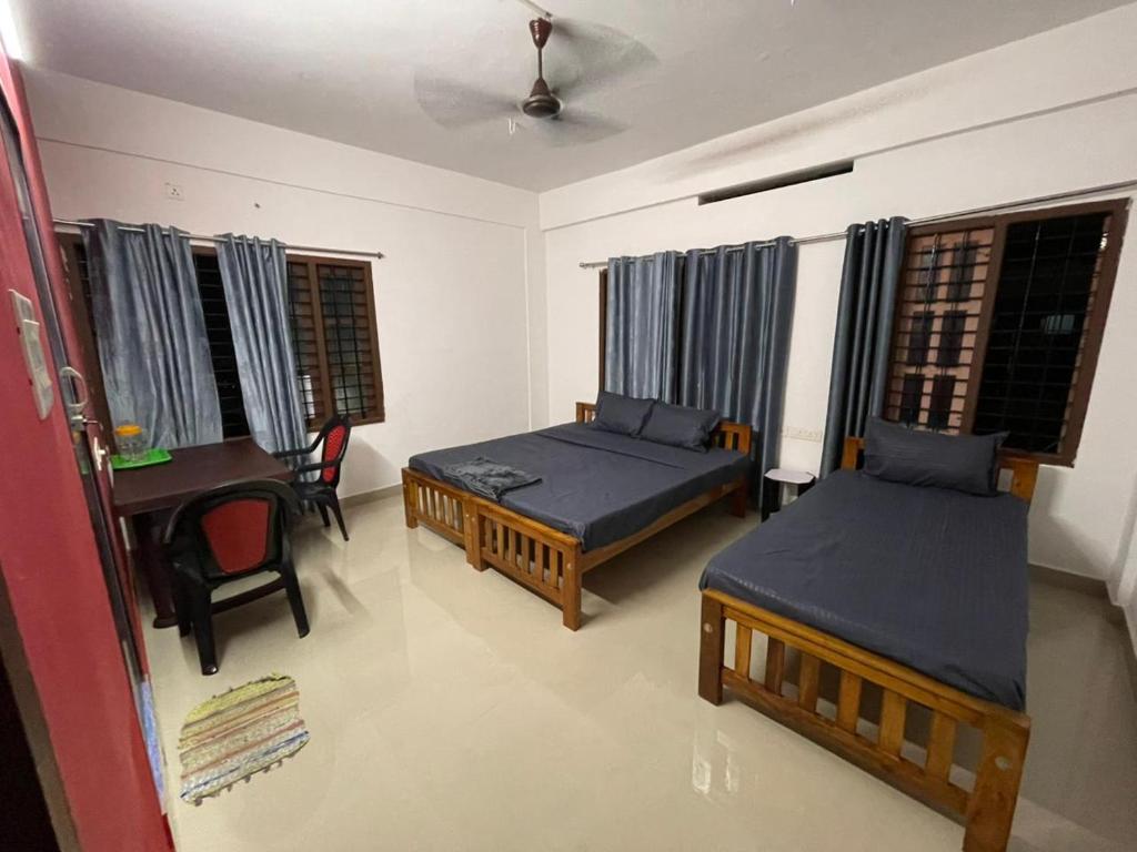 a room with two beds and a desk and a table at Southern Cliff House in Varkala