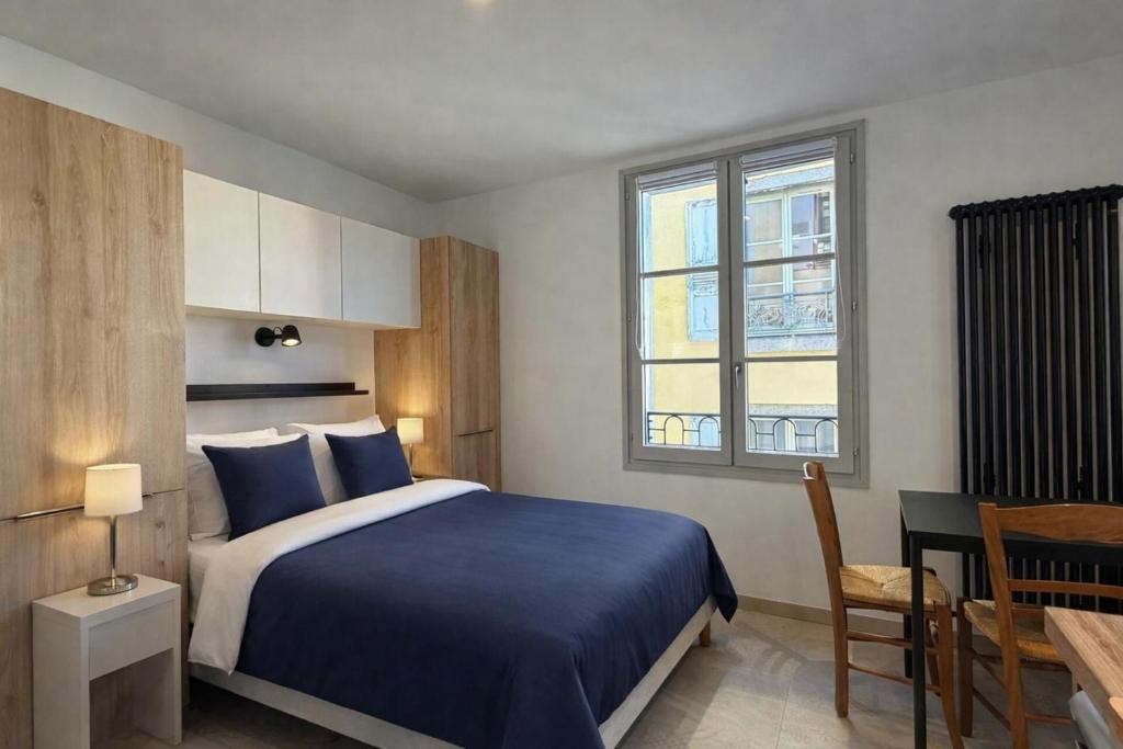 a bedroom with a bed and a table and a window at Les Suites Villeneuve - 2 in Le Puy-en-Velay