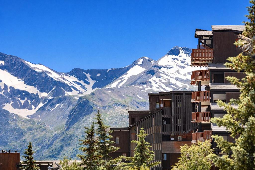 a building with snow covered mountains in the background at Résidence Pierre & Vacances L'Ours Blanc in L'Alpe-d'Huez