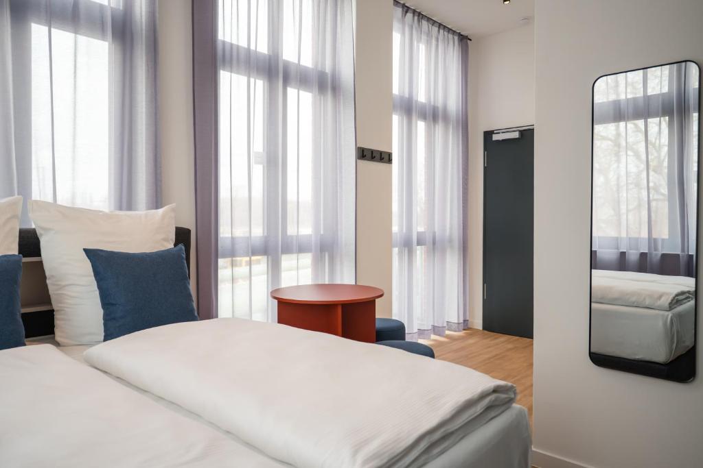 a bedroom with a white bed and a mirror at Homaris Rummelsburg Studios in Berlin