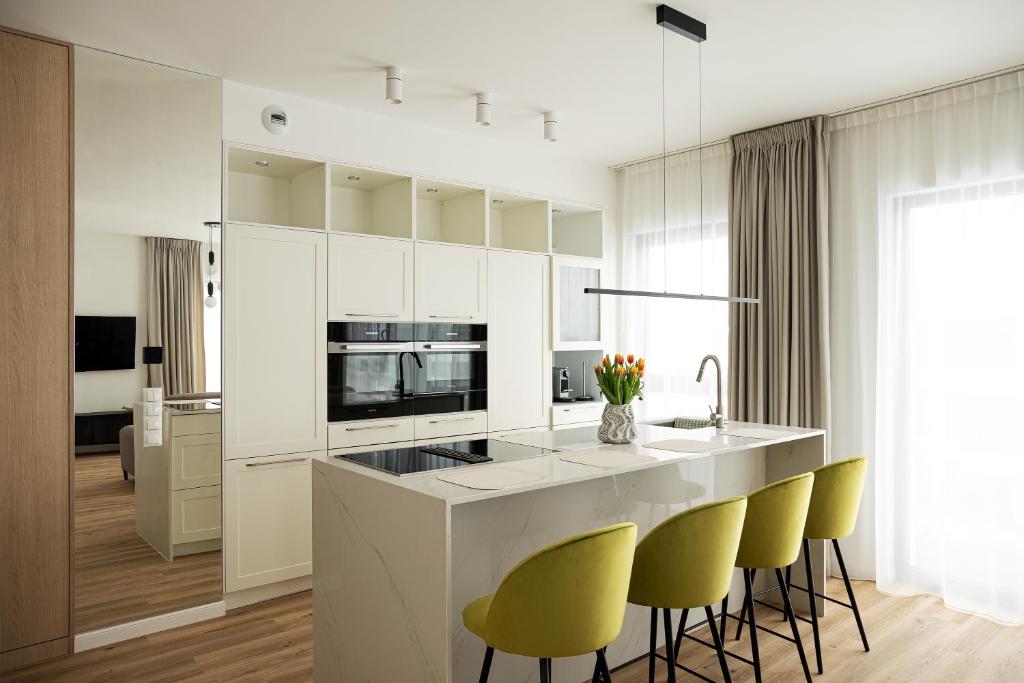 a kitchen with white cabinets and yellow bar stools at Lighthouse View - Sol Marina in Wiślinka