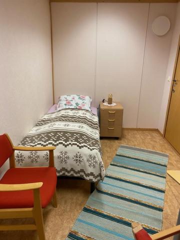 a small bedroom with a bed and a chair at Sentrumovernatting in Kjøllefjord