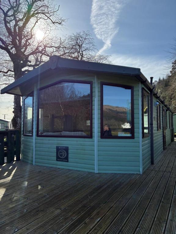 a small blue house with a large window on a deck at The Mosselle No 60 in Ardentinny