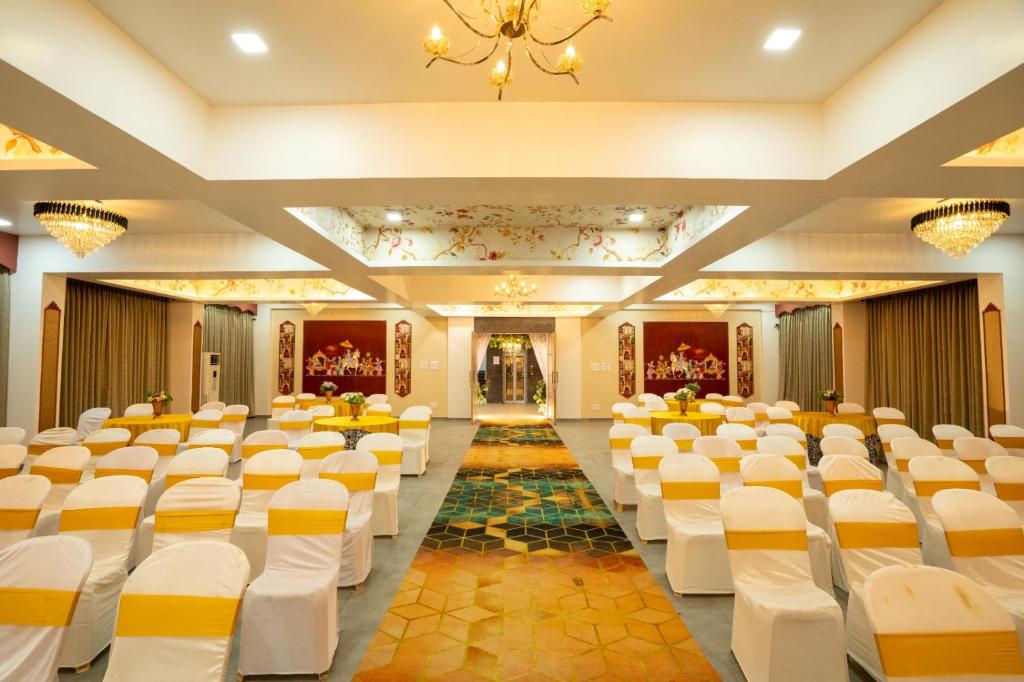 a banquet hall with white chairs and a corridor at Krushnai Resort in Kharakvasla