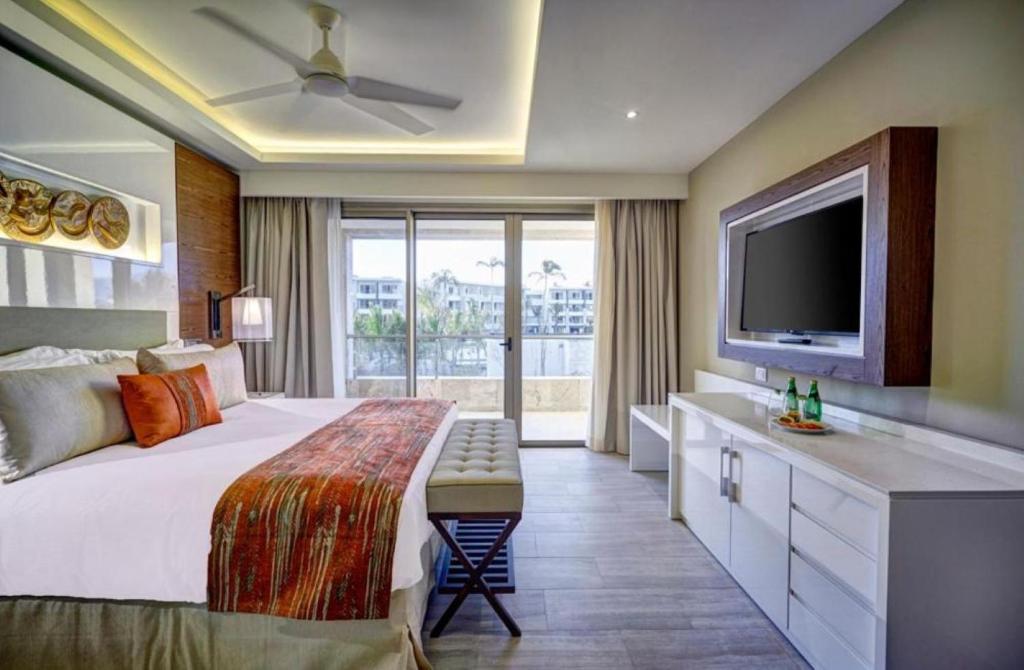 Guest room with king bed, TV, balcony view, and modern decor.