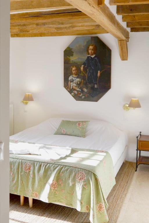 a bedroom with a bed with a painting on the wall at La Roseraie in Barjouville