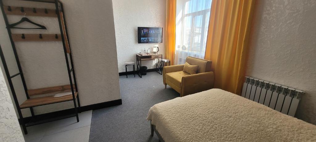 a room with a bed and a chair and a window at Антарес Отель in Shemonaīkha