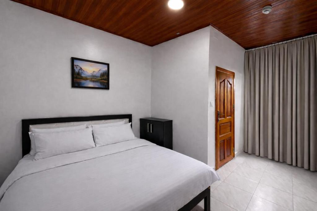 a bedroom with a white bed and a wooden ceiling at RICEM Guest House in Cyuve