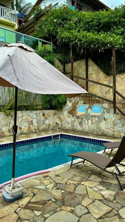 an umbrella and a chair next to a swimming pool at Solar Paraty - Casa perto do centro com psicina in Paraty