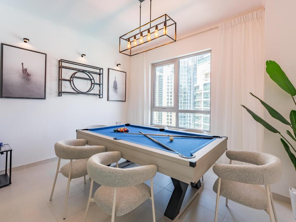 a living room with a pool table and chairs at the 'New York' Condo - 4BR Executive Burj Khalifa Suite in Dubai