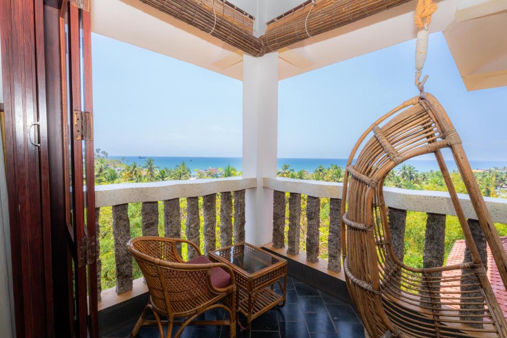 a room with a balcony with chairs and a swing at DrUnni's Ayurveda Resort in Kovalam
