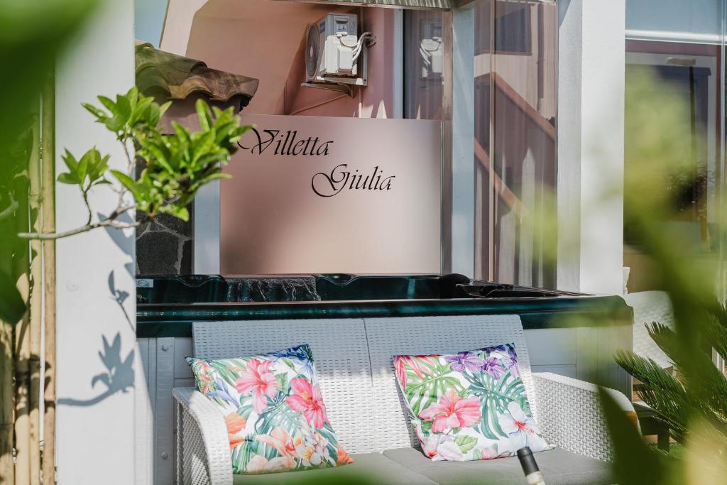 a table and chairs with pillows on a porch at villetta giulia fronte mare in Stintino