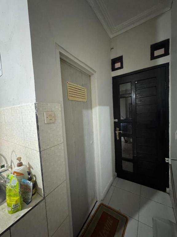 a bathroom with a black door and a tile floor at laksana homestay in Cireungit