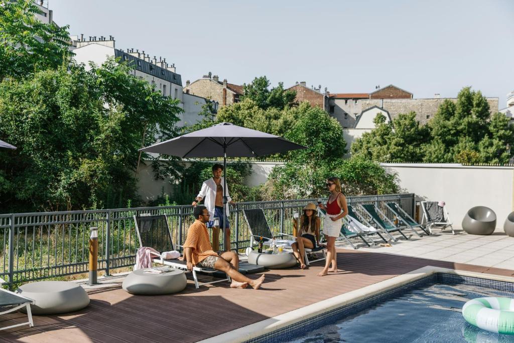 a group of people sitting on lounge chairs next to a pool at The Social Hub Paris La Défense in Puteaux